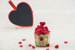 coeurs dans un petit panier en bois tissé et un mot d'amour sur un tableau coeur mettant sur le tissu du sac. photo