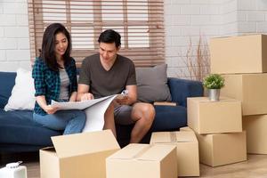 un jeune couple heureux asiatique souriant tient un plan pour des idées de décoration de maison le jour du déménagement dans leur nouvelle maison après avoir acheté un bien immobilier. concept de commencer une nouvelle vie pour un couple nouvellement marié. photo