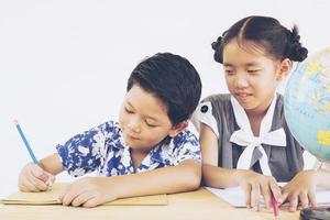 les enfants asiatiques étudient le globe sur fond blanc photo