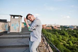 homme macho élégant rêveur en costume gris et lunettes posées sur le toit. photo