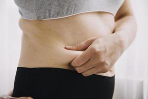 belle grosse femme avec ruban à mesurer, elle utilise sa main pour presser l'excès de graisse isolé sur fond blanc. elle veut perdre du poids, le concept de chirurgie et décomposer les graisses sous le photo