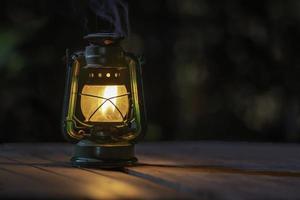 lampe à pétrole antique avec des lumières sur le plancher en bois la nuit photo