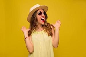 portrait intérieur d'une jolie fille excitée bouche ouverte avec des émotions surprises posant sur fond jaune chapeau habillé et robe d'été. été, vraies émotions, voyager, heureux, sourire photo