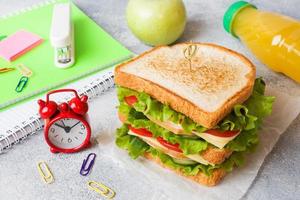 déjeuner sain pour l'école avec sandwich, pomme fraîche et jus d'orange. fournitures scolaires colorées assorties. espace de copie. photo