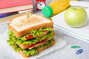 déjeuner sain pour l'école avec sandwich, pomme fraîche et jus d'orange. fournitures scolaires colorées assorties. espace de copie. photo