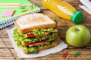 déjeuner sain pour l'école avec sandwich, pomme fraîche et jus d'orange. fournitures scolaires colorées assorties. espace de copie. photo