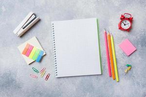 fournitures scolaires, cahiers crayons sur fond gris avec espace de copie.
