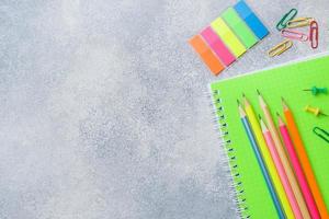 fournitures scolaires, cahiers crayons sur fond gris avec espace de copie.