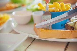 gros plan de personnes mangeant du steak avec des frites de saucisses et un plat de salade - personnes avec concept de restauration rapide photo