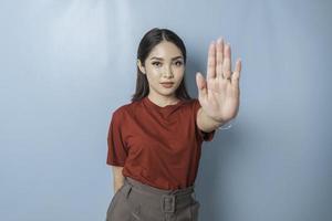 jeune femme asiatique portant un t-shirt rouge sur fond bleu isolé faisant un panneau d'arrêt avec la paume de la main. photo