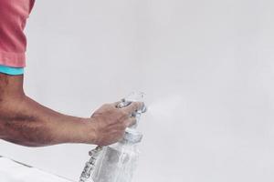 homme travaillant avec une machine à peinture en aérosol pour colorer les meubles dans le processus d'installation d'une nouvelle maison - ouvrier peignant des meubles concept sur place photo