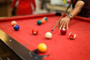 gros plan sur la main d'un homme se préparant à tirer sur la boule blanche avec un ensemble complet de boules de billard photo