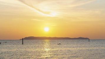 coucher de soleil coloré brillant sur les eaux orange vif de l'océan avec un petit navire flottant. silhouette d'un petit bateau de pêche sur la mer au coucher du soleil. mise au point douce sur les arrière-plans du coucher du soleil.