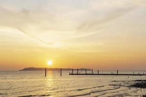 paysage de coucher de soleil coloré brillant sur les eaux orange vif de l'océan. silhouette de touristes marchant, se relaxant et prenant des photos au coucher du soleil sur la plage du coucher de soleil tropical à la plage de koh larn.