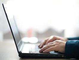 les mains masculines tapent sur un clavier d'ordinateur portable. un homme au bureau écrit sur un ordinateur portable. mise au point sélective photo