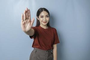 jeune femme asiatique portant un t-shirt rouge sur fond bleu isolé faisant un panneau d'arrêt avec la paume de la main. photo