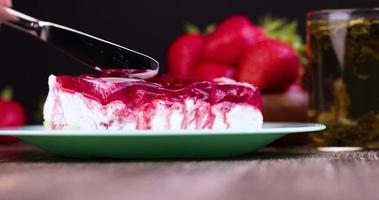 couper le gâteau aux fraises avec de la crème au fromage et de la confiture photo