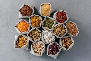 concept d'aliments céréaliers naturels. vue de dessus de petits sacs en tissu autour, composés de fruits secs et de céréales sains. variété mixte. mise à plat