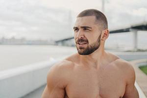 tir extérieur d'un homme barbu avec un torse nu musclé concentré à distance, pense à obtenir des résultats sportifs, se prépare pour l'entraînement du matin, a un corps bien soigné. remise en forme, sport, style de vie photo