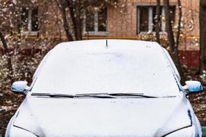 première neige sur la voiture devant l'immeuble photo