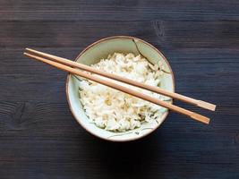 baguettes au-dessus du riz bouilli dans une tasse sur une table sombre photo