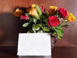 feuille de papier vierge et roses rouges et jaunes photo