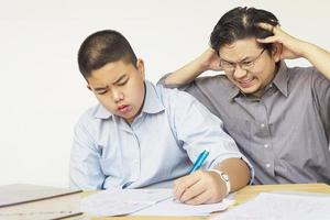 père asiatique enseignant sérieusement les devoirs à son fils de 14 ans photo