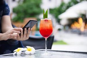 dame utilisant un téléphone portable se détendre dans un jardin verdoyant avec fond de boisson non alcoolisée - concept de style de vie des personnes et de la technologie photo