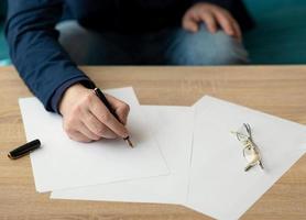 homme d'affaires au bureau écrit une lettre ou signe un document sur un morceau de papier blanc avec un stylo plume avec plume. gros plan des mains d'un homme d'affaires en costume photo