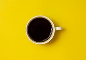 vue de dessus de la tasse de café noire sur fond jaune photo