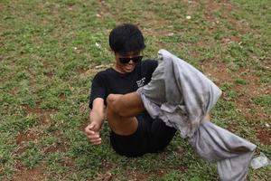 sumedang, indonésie juillet 2022 l'excitation d'un jeune homme asiatique fait des activités sortantes ou joue à des jeux dans l'herbe. photo