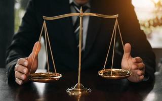 avocat masculin au bureau avec échelle en laiton sur table en bois. concept de justice et de droit photo