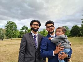 2 jeunes hommes asiatiques marchent avec un bébé garçon au parc public local de luton england uk photo