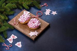 beignet glacé rose et guimauve avec des décorations de noël sur une planche à découper en bois photo