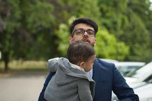 un père pakistanais asiatique tient son bébé de 11 mois dans un parc local photo