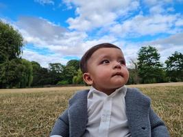 Mignon petit bébé bébé pose dans un parc public local de la ville de Luton en Angleterre Royaume-Uni photo