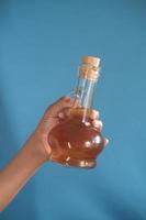 tenant une bouteille en verre de vinaigre de pomme photo