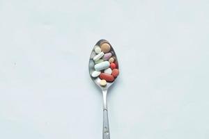vue de dessus de nombreuses pilules et capsules colorées sur une cuillère blanche photo