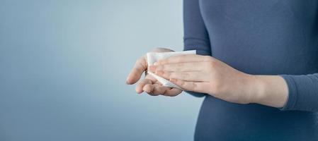 jeune femme se nettoyant les mains en utilisant une serviette antibactérienne blanche sur fond gris. photo avec espace de copie.