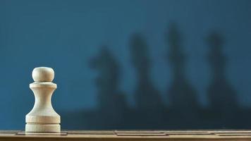 pion d'échecs avec ombre floue du roi, reine, cheval sur fond gris foncé. photo avec espace de copie.