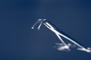 clip chirurgical au flou artistique sur fond bleu. la poignée de l'instrument médical dans le flou. photo