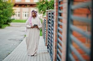 homme arabe du moyen-orient posé dans la rue contre un bâtiment moderne avec une tablette à portée de main. photo