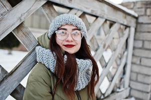 portrait de jeune fille brune en écharpe et chapeau gris, lunettes par temps froid. photo