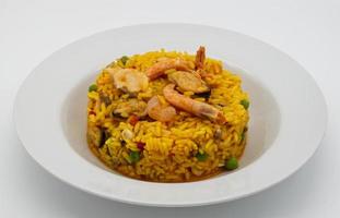 paella espagnole traditionnelle dans un plat blanc isolé sur fond blanc. photo