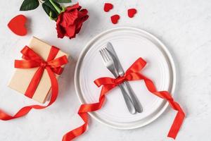 assiette avec vaisselle, ruban, cadeau et roses pour le concept de repas spécial de la saint-valentin. photo