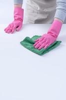 la jeune femme de ménage en tablier porte des gants roses pour nettoyer la table, concept de prévention de l'infection virale, service d'entretien ménager, gros plan.