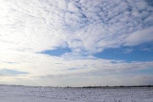 beaux nuages dans le ciel donnant sur un champ agricole couvert de neige. photo