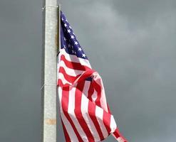drapeau américain à un mât se déplaçant lentement dans le vent contre le ciel photo