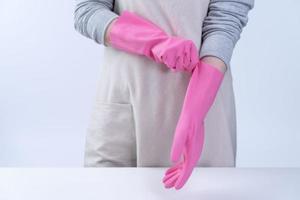 la jeune femme de ménage en tablier porte des gants roses pour nettoyer la table, concept de prévention de l'infection virale, service d'entretien ménager, gros plan.