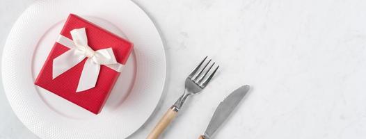 assiette avec vaisselle, ruban, cadeau et roses pour le concept de repas spécial de la saint-valentin. photo